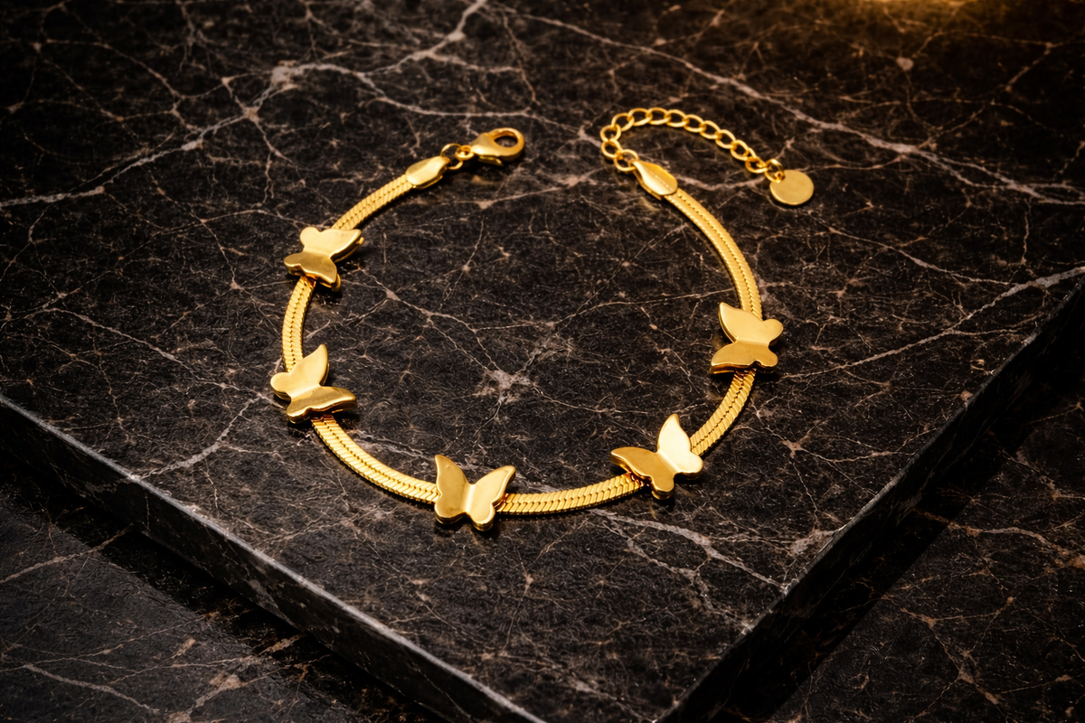 Luxurious gold chain bracelet with elegant butterfly charms on dark veined marble.