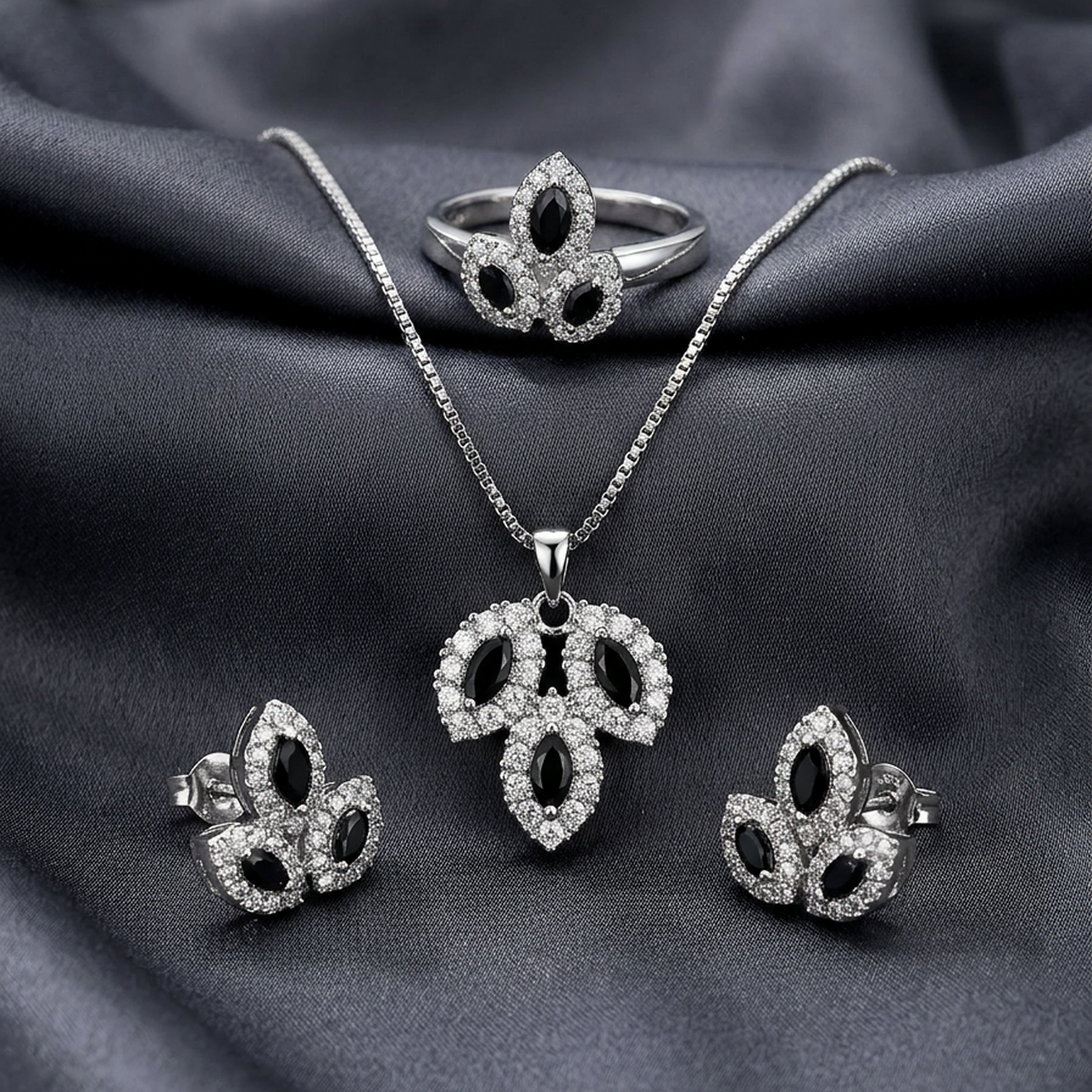 Silver leaf stone jewelry set by Zaraya Store with black marquise-cut and clear pavé stones, including necklace, ring, and earrings on dark fabric.
