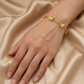 Gold-plated bracelet by Zaraya Store featuring multiple textured butterfly charms on a woman's wrist against golden fabric.
