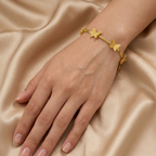 Gold-plated bracelet by Zaraya Store featuring multiple textured butterfly charms on a woman's wrist against golden fabric.