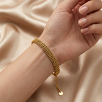 Gold braided mesh bracelet by Zaraya Store, worn on a wrist with an adjustable chain and 'M' initial charm on champagne satin.