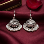 Pearl Jhumki earrings by Zaraya Store, two silver domed earrings with intricate designs and dangling white pearls on maroon fabric.