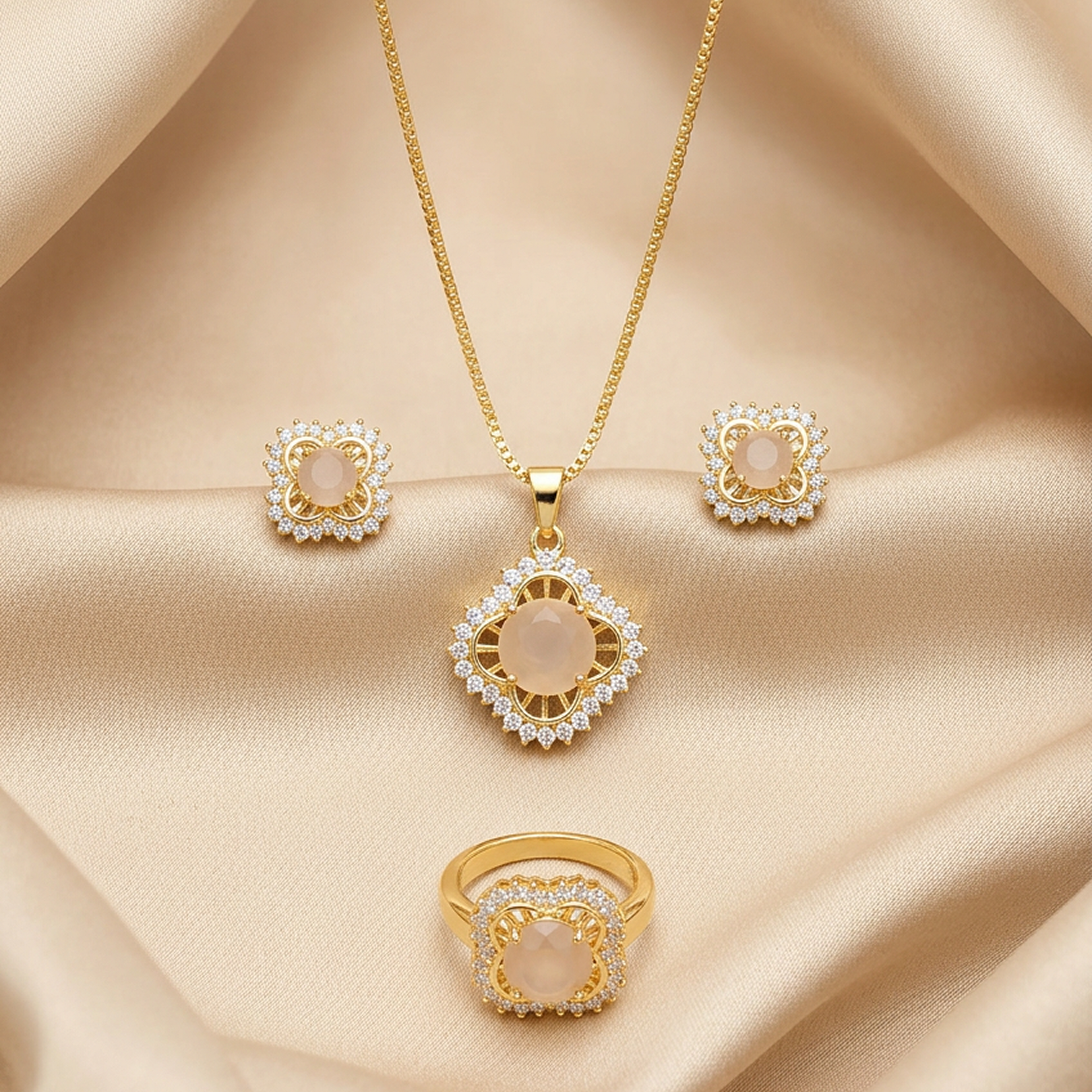 Royal gold jewelry set with light peach round stones and sparkling gems, including a necklace, earrings, and ring, displayed on satin.