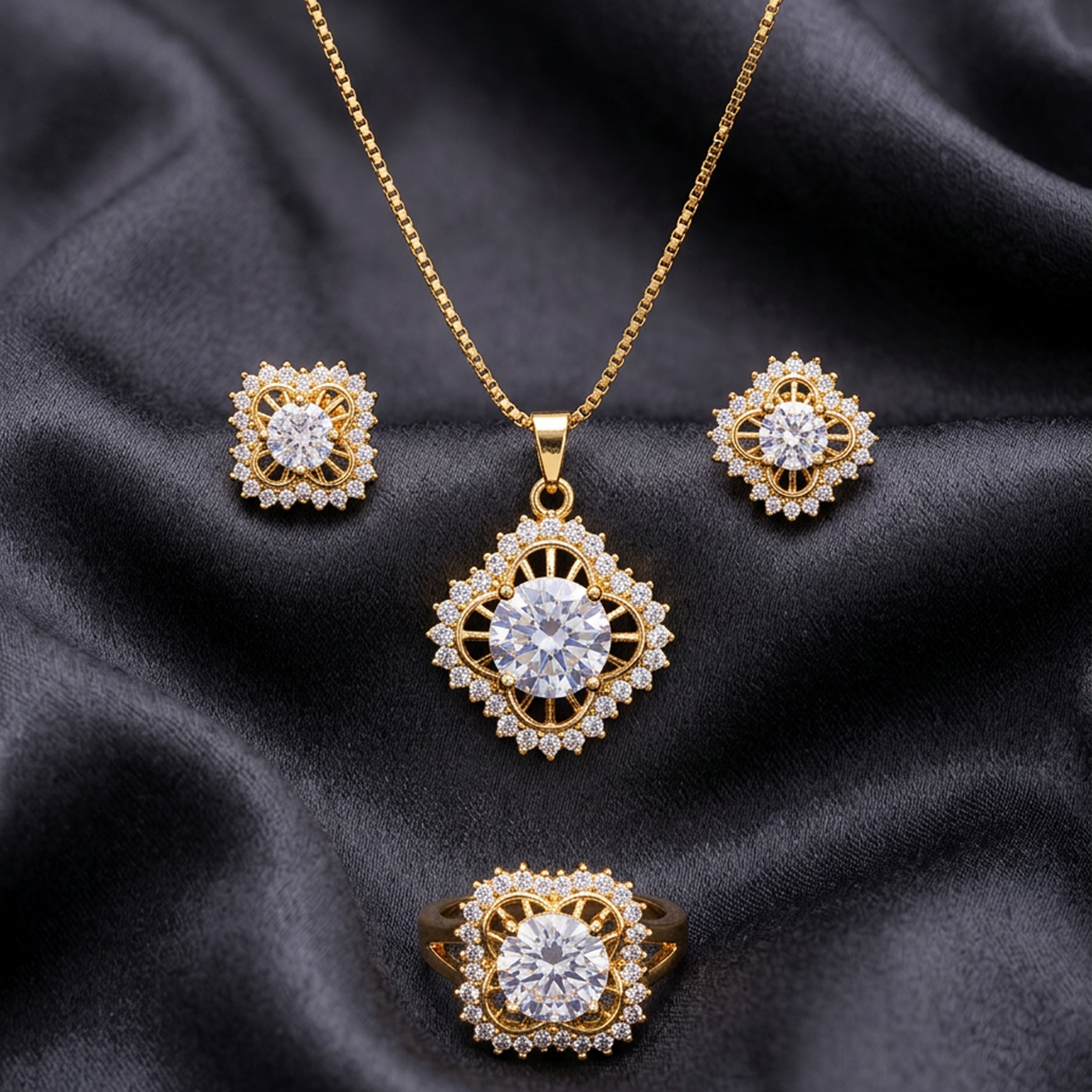Royal gold jewelry set with white round crystals, featuring a necklace, earrings, and ring, on black satin.