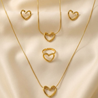 4-piece gold stainless steel heart jewelry set by Zaraya Store, featuring two necklaces, a ring, and two earrings on cream fabric.