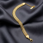 Gold and pavé crystal stack bracelet by Zaraya Store, with three woven gold chains and a lobster clasp on dark fabric.