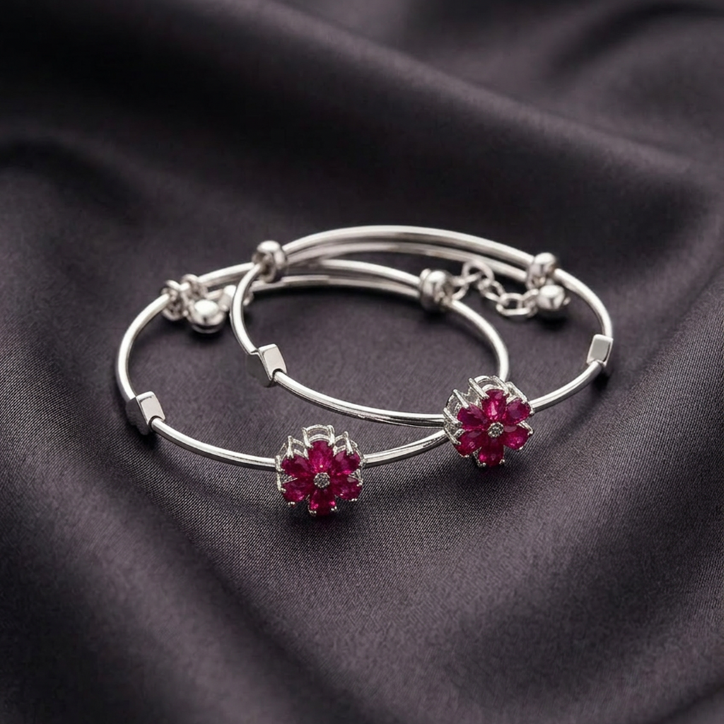 Pair of silver stainless steel adjustable bracelets by Zaraya Store with ruby red floral designs, resting on dark fabric.