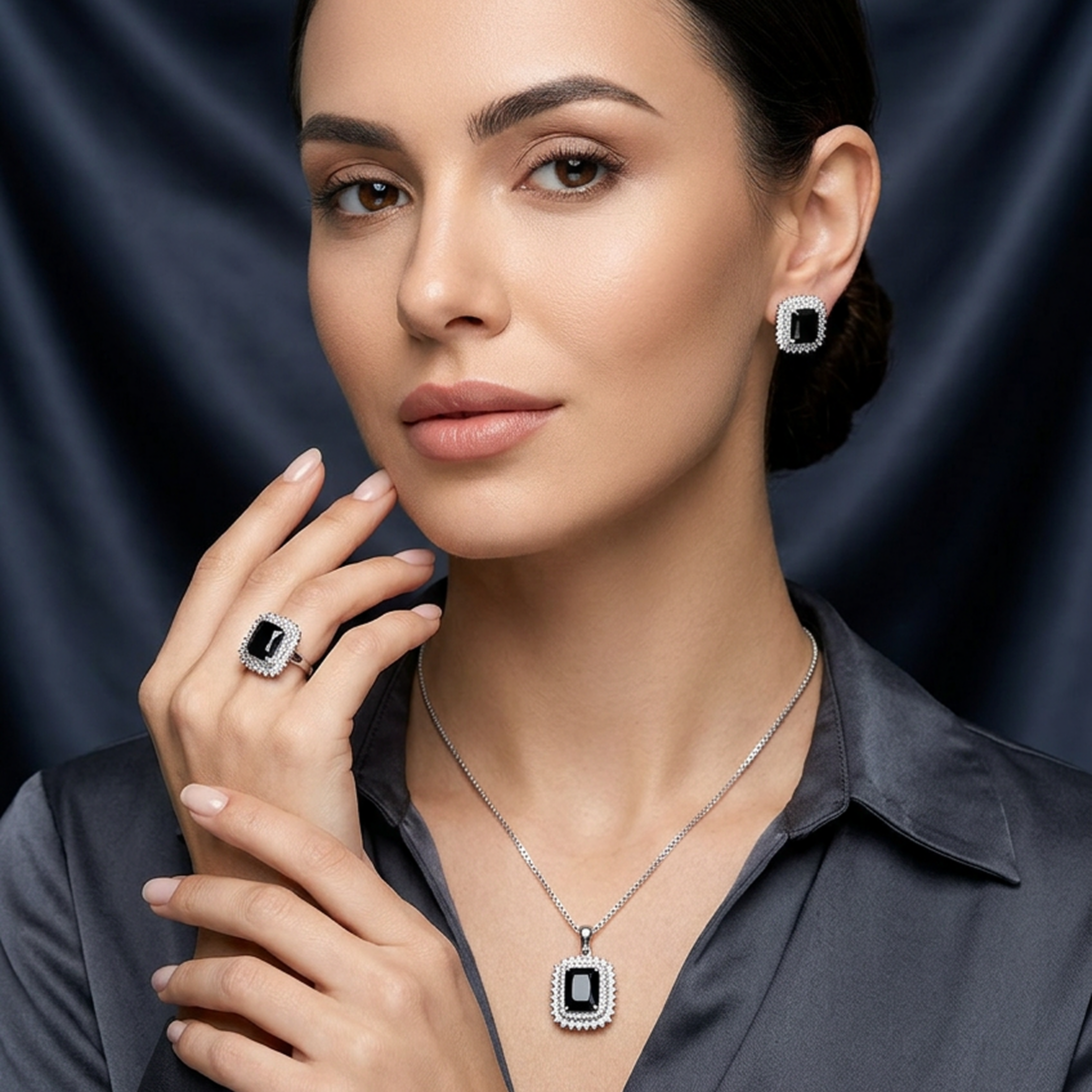 Silver jewelry set with square black stones and white halos worn by a woman in a dark gray collared shirt.
