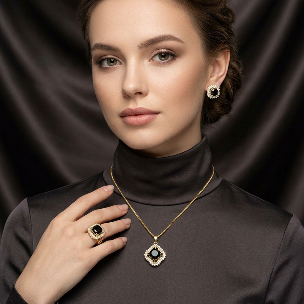 Gold jewelry set with black stones, including a square pendant necklace, round stud earrings, and a ring, worn by a woman.