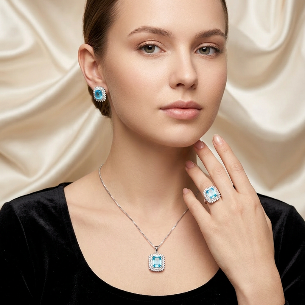 Elegant silver jewelry set with light blue square stones, including a necklace, earrings, and ring, worn by a model.