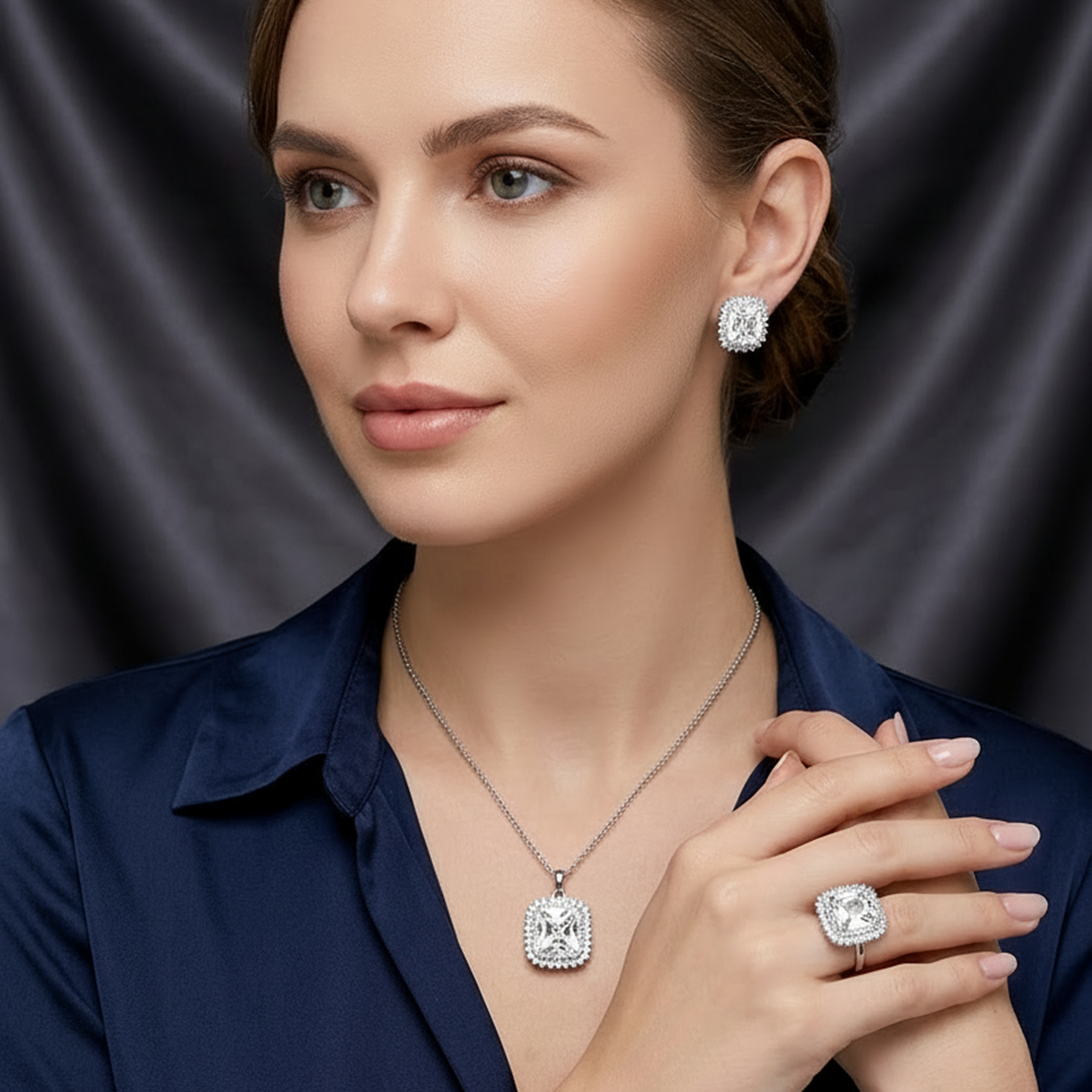 Elegant silver jewelry set with white square stones, including a ring, necklace, and earrings, worn by a woman in a navy shirt.
