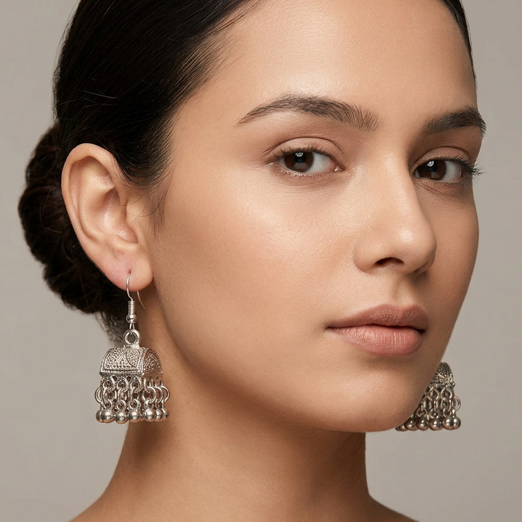 Antique silver pearl jhumki earrings by Zaraya Store, with a textured bell and dangling metallic beads, worn by a woman.