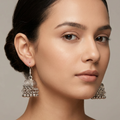 Antique silver pearl jhumki earrings by Zaraya Store, with a textured bell and dangling metallic beads, worn by a woman.
