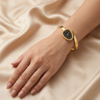Gold stainless steel snake wrap bracelet watch by Zaraya Store, featuring a black dial with Roman numerals, worn on a female wrist against champagne satin.