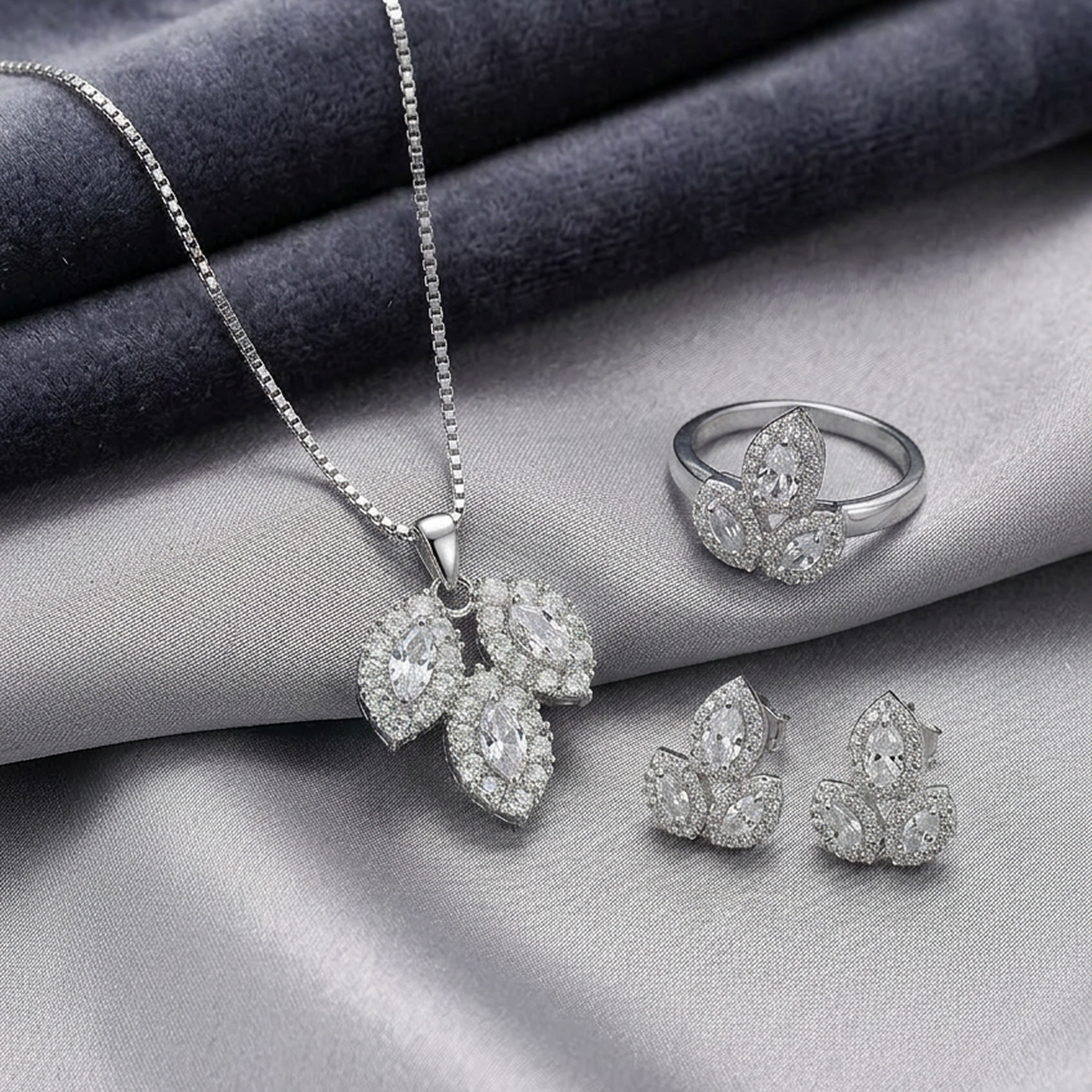 Silver leaf-shaped stone jewelry set by Zaraya Store, including a necklace, ring, and earrings, on a grey fabric.